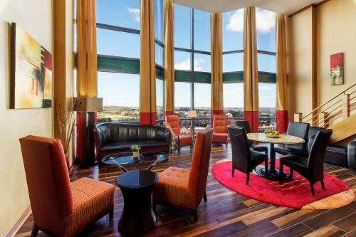 a living room with chairs and tables and large windows at Hilton Charlotte University Place in Charlotte