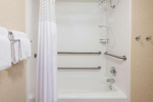 a bathroom with a shower and a white tub at Hampton Inn Charlotte University Place in Charlotte