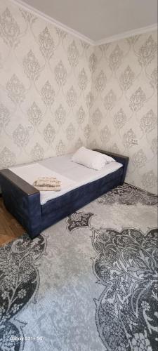 a small bed in a room with a wall at Cozy apartment in Tashkent