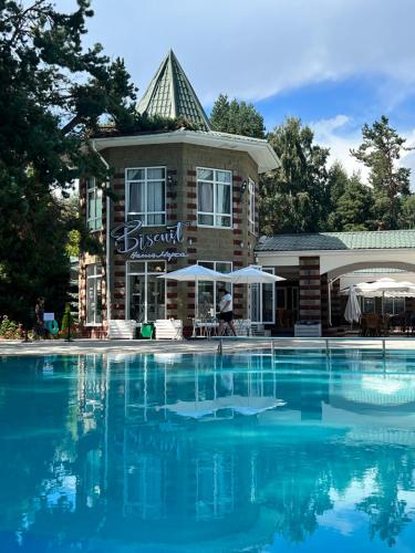 a hotel with a swimming pool in front of a building at Радуга Иссык-Куль in Chon-Sary-Oy