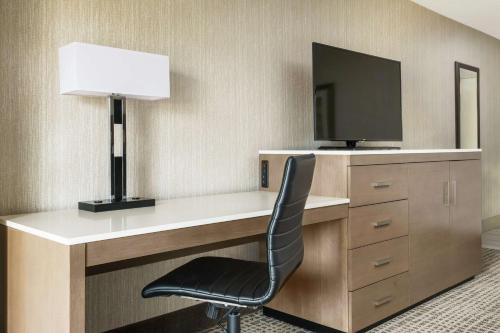 a desk with a television and a chair in a room at DoubleTree by Hilton Orlando Airport Hotel in Orlando