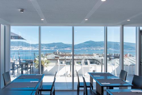 a restaurant with tables and chairs and a view of the water at Hotel Maroa Vigo in Vigo