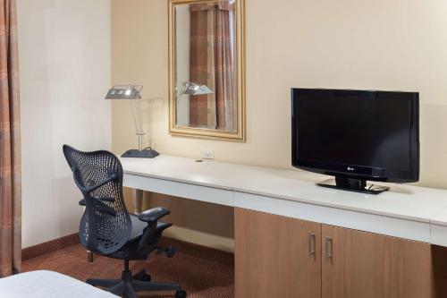 a room with a desk with a television and a chair at Hilton Garden Inn McAllen Airport in McAllen