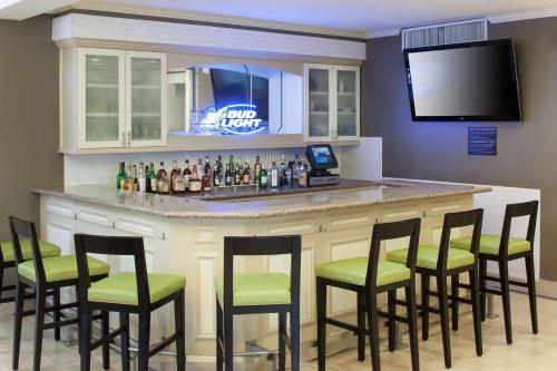 a bar with green chairs and bottles of alcohol at Hilton Garden Inn McAllen Airport in McAllen
