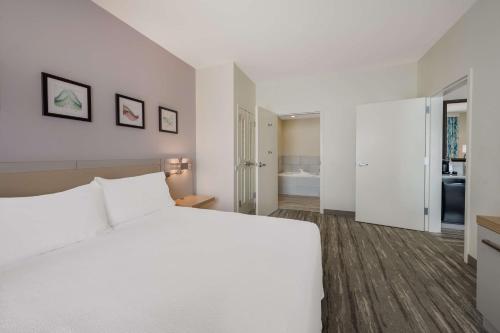 a white bedroom with a large bed and a bathroom at Hilton Garden Inn Rockford in Rockford