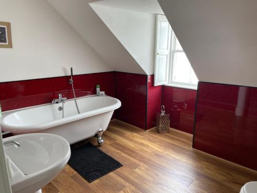 a bathroom with a white tub and red walls at The Old Rectory in Inveraray