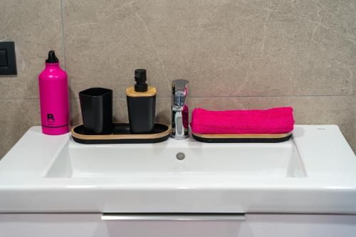 a white bathroom sink with a pink towel and cosmetics at Yuli in Puerto de la Cruz