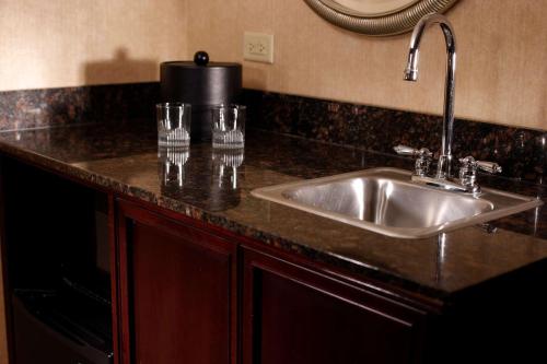 a kitchen counter with a sink and glasses on it at Embassy Suites Lubbock in Lubbock