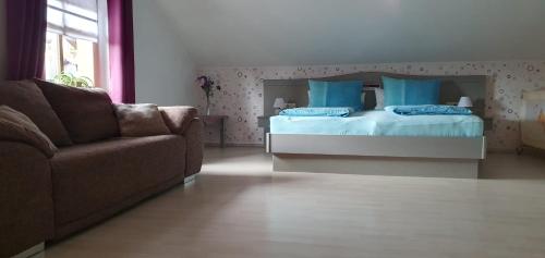 a bedroom with a bed with blue pillows and a couch at Haus Sonntal in Bodenmais