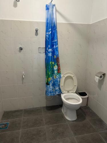 uma casa de banho com um WC e uma cortina de chuveiro em Mango Tree Budget Home Stay em Homagama