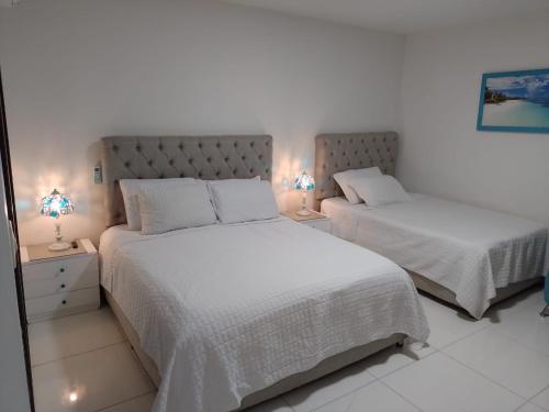 a bedroom with two beds with white sheets and lamps at Hotel Colonial Andino - Parque principal de Pitalito in Pitalito