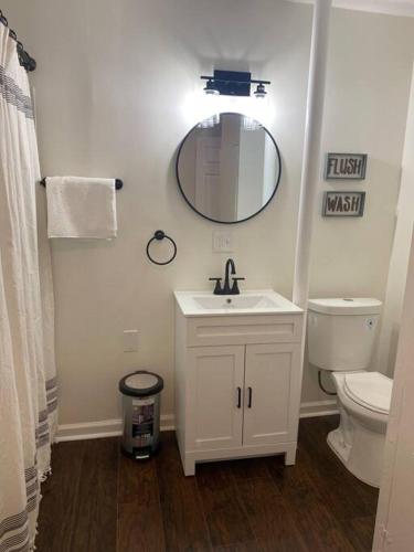 ein Badezimmer mit einem Waschbecken, einem WC und einem Spiegel in der Unterkunft Boho Hideway! in New Albany