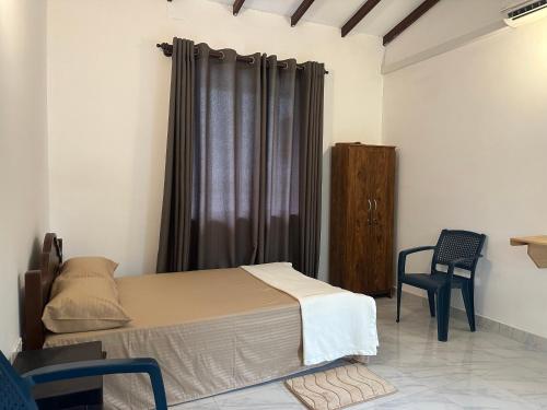 a bedroom with a bed and a chair and a window at Mango Tree Budget Home Stay in Homagama