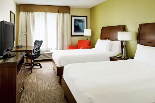 a hotel room with two beds and a desk and a television at Hilton Garden Inn Lake Mary in Lake Mary