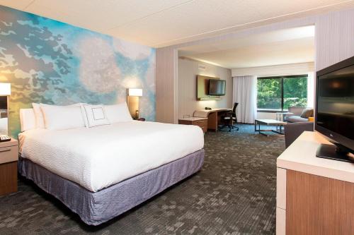 a hotel room with a bed and a flat screen tv at Courtyard Binghamton in Vestal