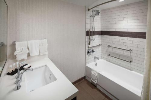 La salle de bains blanche est pourvue d'une baignoire et d'un lavabo. dans l'établissement Embassy Suites Tysons Corner, à Tysons Corner