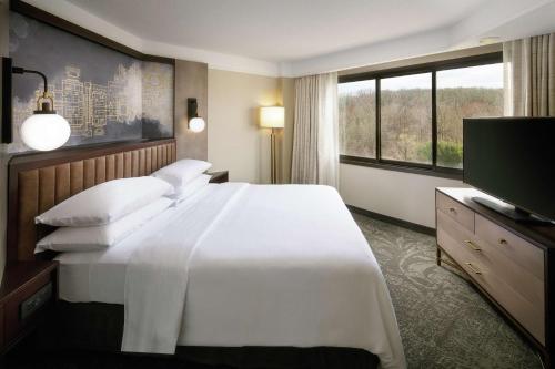a hotel room with a large white bed and a television at Embassy Suites Tysons Corner in Tysons Corner