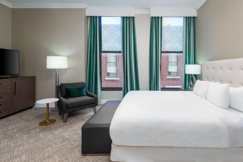 una habitación de hotel con una cama grande y una silla en The Pennywell St Louis Downtown a Hilton Hotel, en Saint Louis