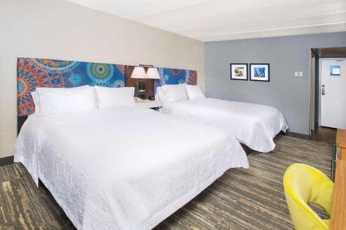 a hotel room with two beds and a yellow chair at Hampton Inn & Suites Annapolis in Annapolis