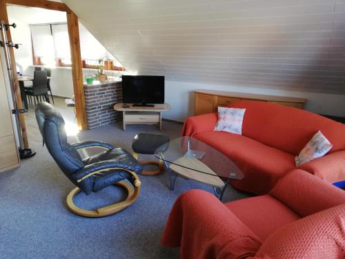 a living room with a red couch and a chair at Ferienwohnung „An der olen Au“ in Tönnhausen