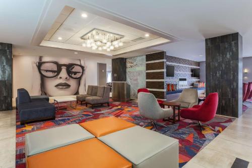 a waiting room with chairs and a large picture of a woman with glasses at DoubleTree by Hilton Atlanta Airport in Atlanta