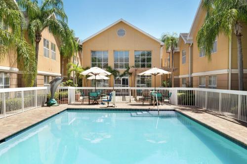 a swimming pool with chairs and umbrellas in front of a building at Homewood Suites by Hilton St. Petersburg Clearwater in Clearwater