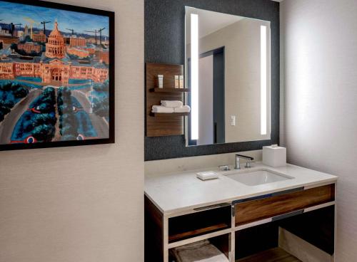 a bathroom with a sink and a painting on the wall at Hilton Garden Inn Austin University Capitol District in Austin