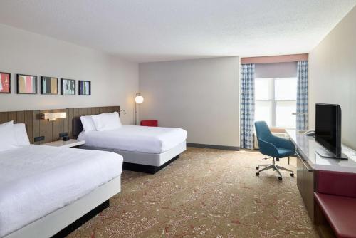 a hotel room with two beds and a desk and a television at Hilton Garden Inn Bloomington in Bloomington