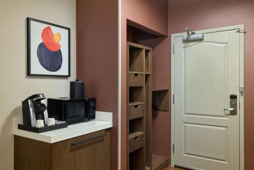 a room with a door leading to a kitchen with a microwave at Hilton Garden Inn Bloomington in Bloomington
