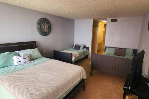 a bedroom with two beds and a clock on the wall at Aliki Atrium Beachfront Condo in Ormond Beach