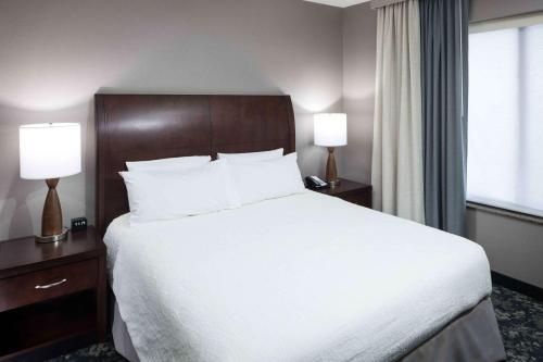 a bedroom with a large bed with white sheets and two lamps at Hilton Garden Inn Detroit/Novi in Novi
