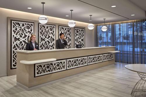 two people standing at a counter in a lobby at Homewood Suites By Hilton Long Beach Airport in Long Beach