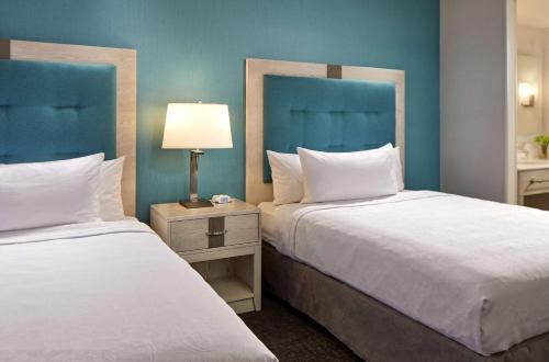 two beds in a hotel room with blue walls at Homewood Suites By Hilton Long Beach Airport in Long Beach