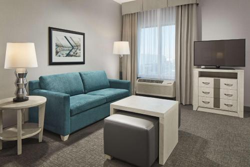 a living room with a blue couch and a tv at Homewood Suites By Hilton Long Beach Airport in Long Beach