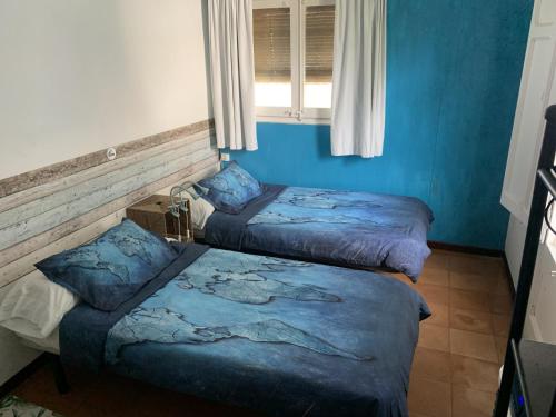 two beds in a room with blue walls and a window at Can Cocollona in Girona