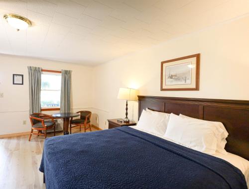 Habitación de hotel con cama con manta azul en Chatham Travel Lodge, en Old Chatham