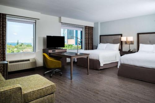 マイアミにあるHampton Inn & Suites Miami Wynwood Design District, FLのベッド2台、デスク、テレビが備わるホテルルームです。