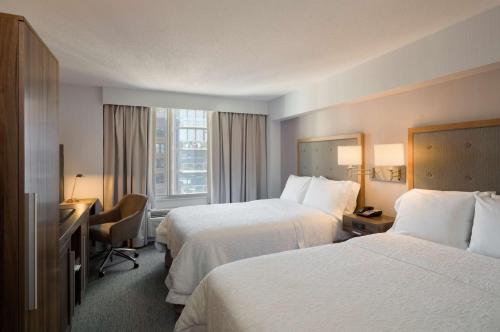 a hotel room with two beds and a desk at Hampton Inn Manhattan Chelsea in New York