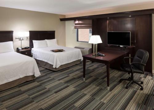 a hotel room with two beds and a desk and a television at Hampton Inn & Suites Omaha-Downtown in Omaha