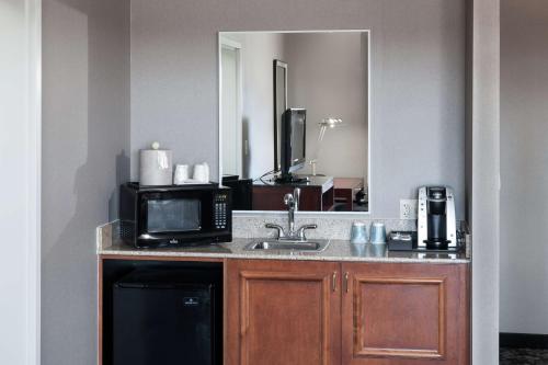 a kitchen with a sink and a microwave and a mirror at Hilton Garden Inn Lake Forest Mettawa in Lake Forest