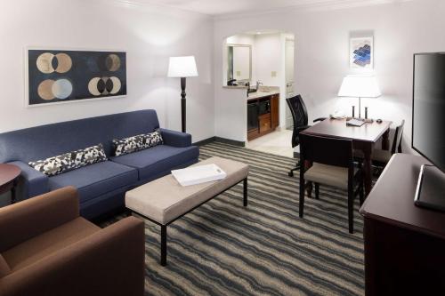 a living room with a blue couch and a desk at Embassy Suites by Hilton Tampa Brandon in Tampa