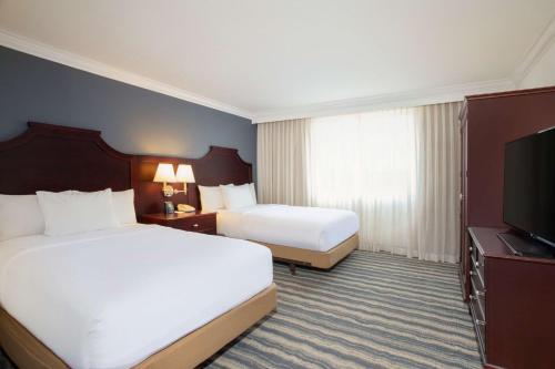 a hotel room with two beds and a flat screen tv at Embassy Suites by Hilton Tampa Brandon in Tampa