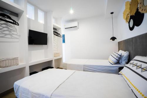 a hotel room with two beds and a tv at Mousikorama Apartments in Faliraki