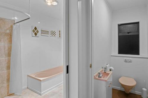 La salle de bains est pourvue d'une baignoire, d'un lavabo et de toilettes. dans l'établissement Taupo Beachfront Escape 12min to Town - Free Wifi, à Waitahanui