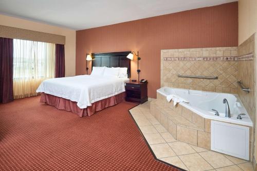 ein Hotelzimmer mit einem Bett und einer Badewanne in der Unterkunft Hampton Inn & Suites Austin South Buda in Buda