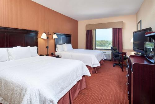 a hotel room with two beds and a flat screen tv at Hampton Inn & Suites Austin South Buda in Buda