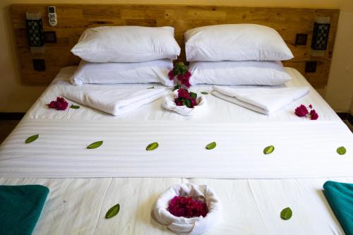 a bed with white sheets and flowers on it at Ninos K.Guraidhoo in Guraidhoo