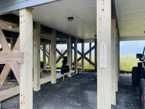 a building with wooden beams and a person sitting in a chair at Serenitee in Holden Beach