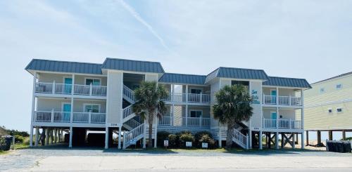 a large apartment building with palm trees in front of it at Next 2 Paradise-203 in Holden Beach
