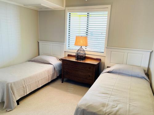 a bedroom with two beds and a table with a lamp at The Skipper condo in Holden Beach